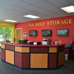 AA Self Storage office interior in Lynchburg VA showing front desk, red accent wall with AA Self Storage signage, and customer service area