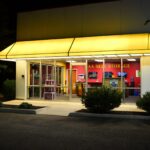 AA Self Storage office entrance at night in Lynchburg VA with bright yellow awning, red interior wall, and 